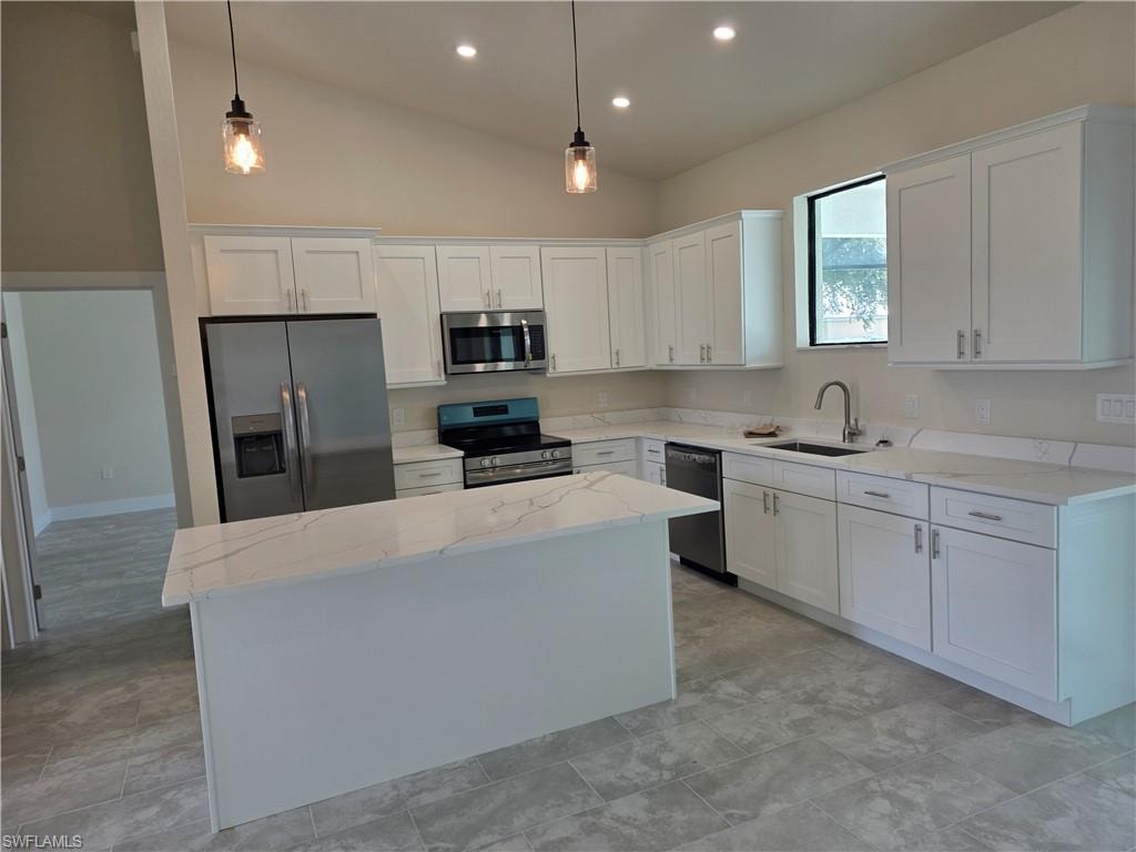 Contemporary kitchen featuring an island, white shaker cabinetry, stainless steel appliances, and light-toned countertops