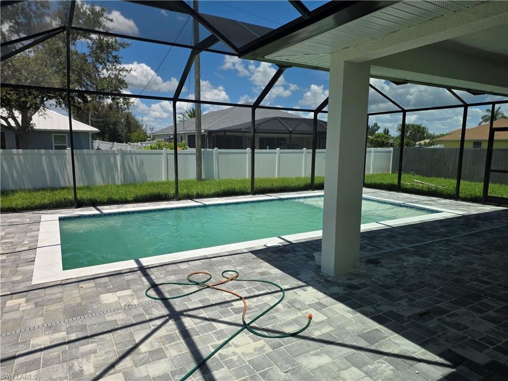Screened outdoor living area featuring a rectangular pool with white coping, paver patio, and white privacy fencing