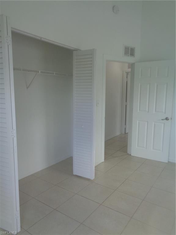 Unfurnished bedroom 1 with a closet, light tile patterned floors, and a towering ceiling