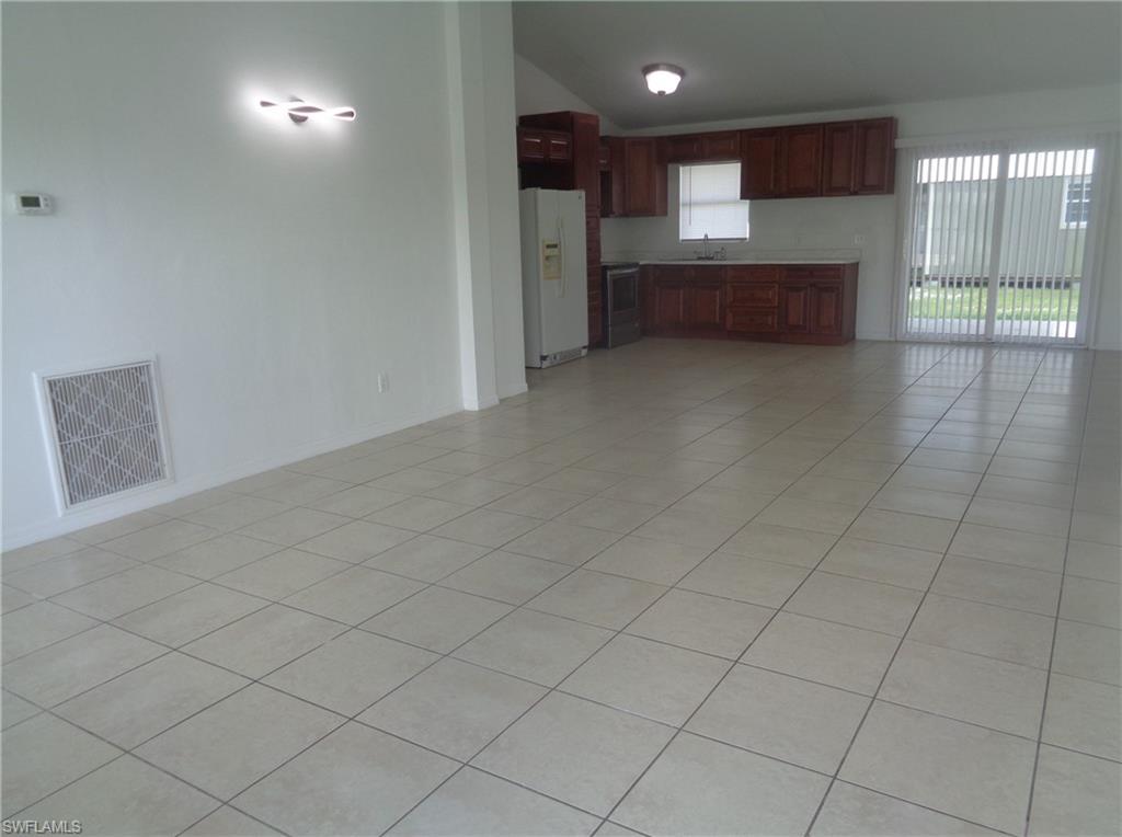 Unfurnished living room with lofted ceiling and light tile patterned floors