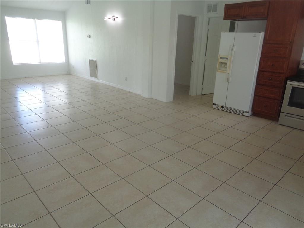 Unfurnished living room featuring light tile patterned floors and baseboards