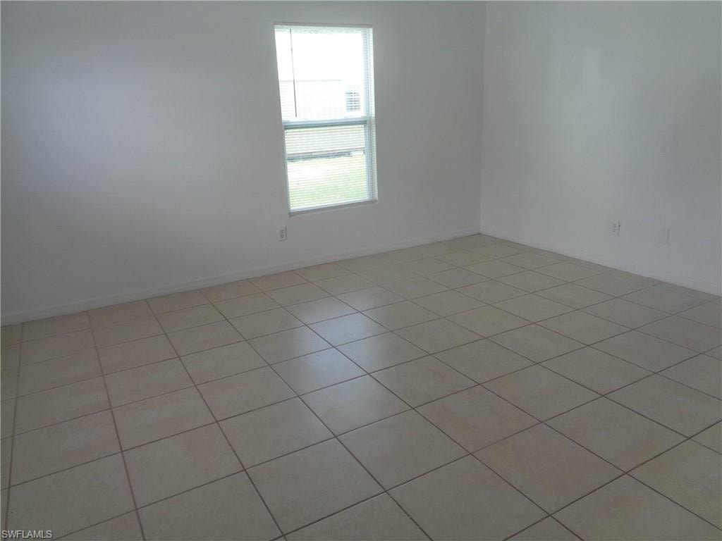 Unfurnished master bedroom with light tile patterned flooring and baseboards