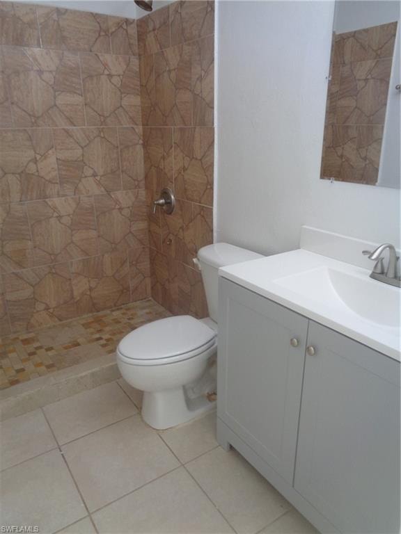 Bathroom with vanity, tiled shower, and tile patterned floors