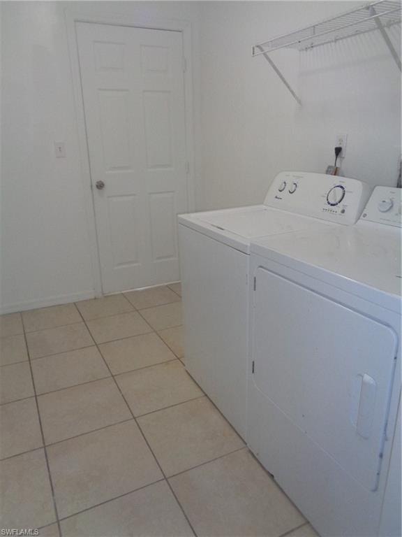 Washroom featuring washing machine and dryer and light tile patterned flooring