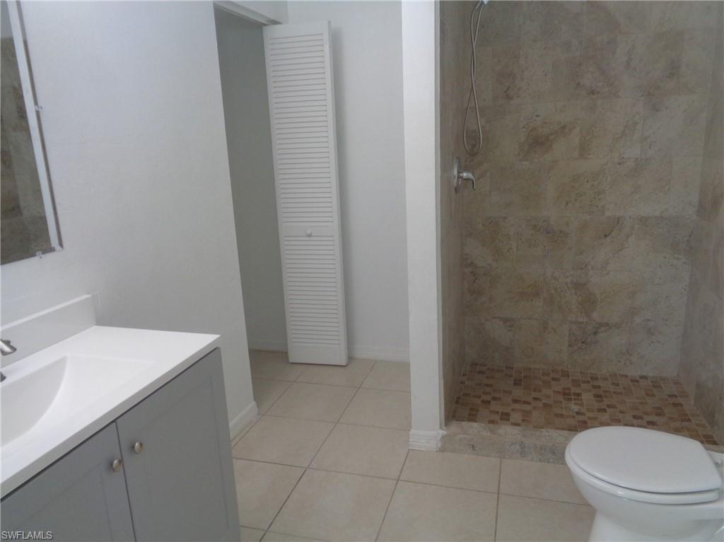 Master bedroom bathroom featuring vanity, tiled shower, tile patterned floors, and a closet