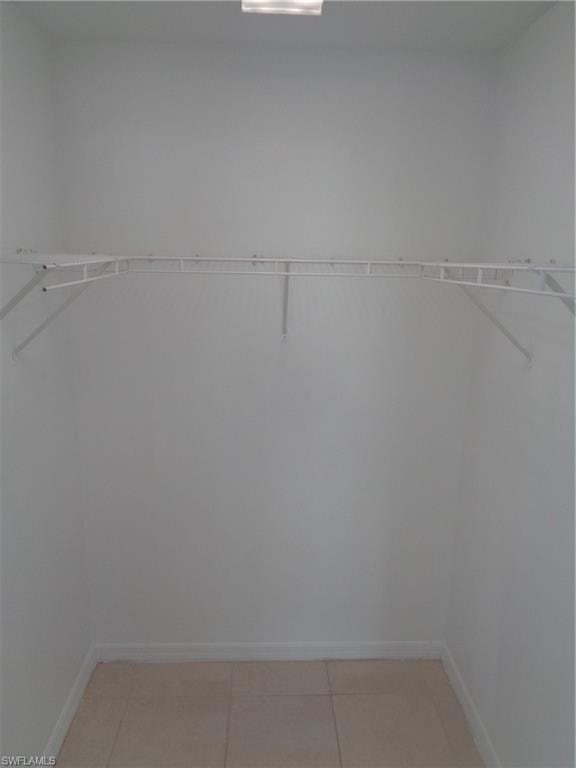 Master bedroom spacious walk-in closet featuring light tile patterned floors