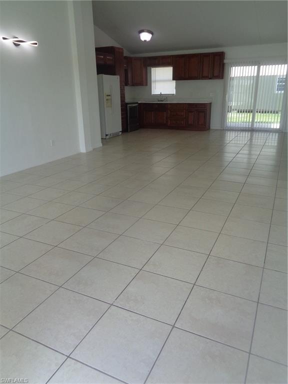 Unfurnished living room featuring lofted ceiling and light tile patterned flooring