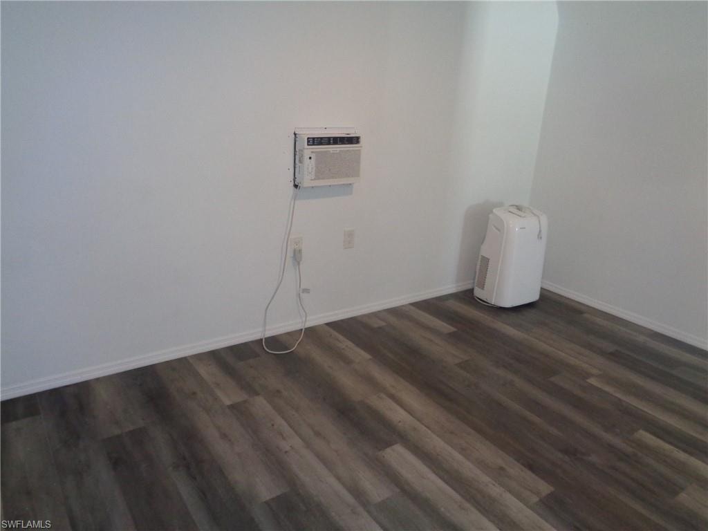 View of unfurnished master bedroom and an AC wall unit of the permitted 2 bed / 1 bath apartment featuring dark wood-style flooring and a wall mounted air conditioner