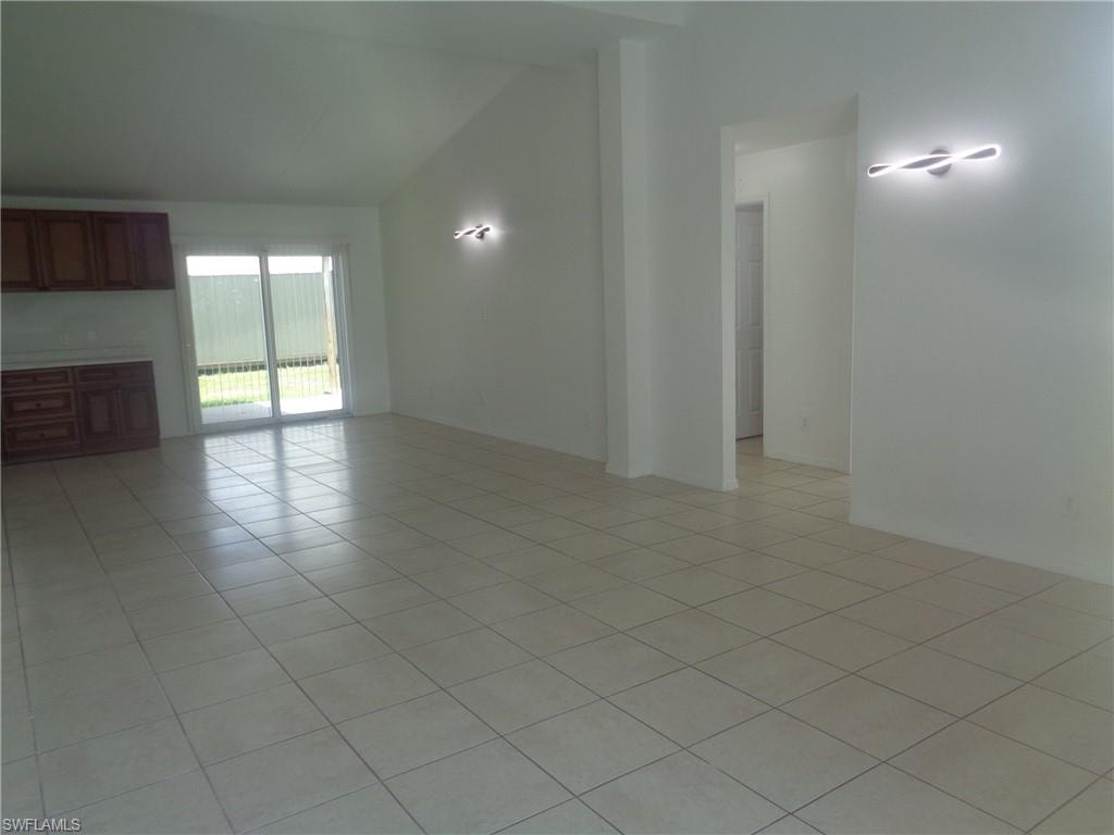 Unfurnished living room with vaulted ceiling and light tile patterned flooring
