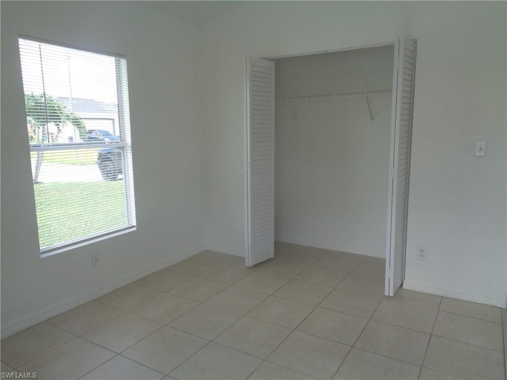 Unfurnished bedroom 1 with a closet and light tile patterned flooring