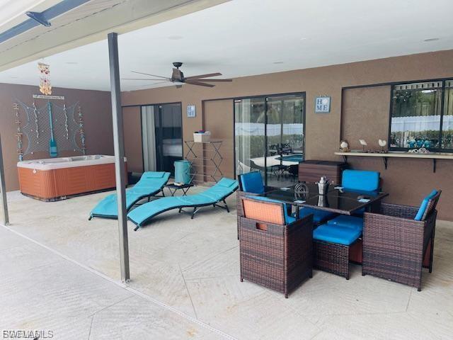 View of patio with a hot tub, a ceiling fan, and outdoor dining space