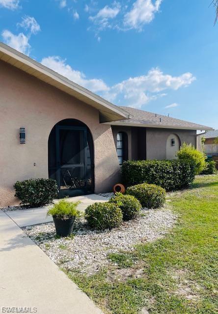 View of property exterior with stucco siding and a lawn