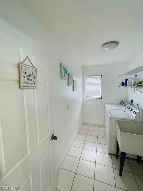 Washroom with independent washer and dryer and light tile patterned flooring