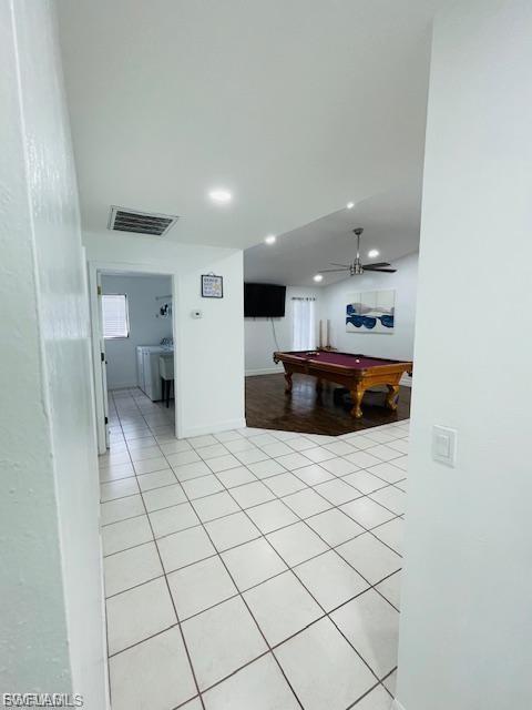 Corridor featuring washing machine and clothes dryer, light tile patterned flooring, and recessed lighting