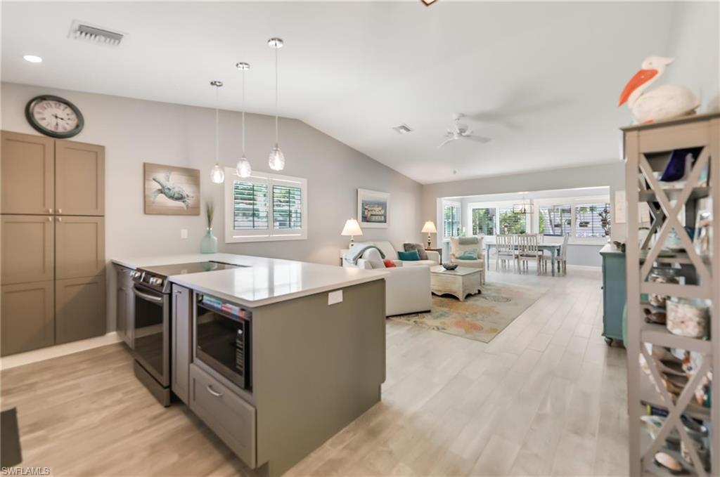 Kitchen featuring a peninsula, lofted ceiling, stainless steel appliances, a ceiling fan, and light wood-style floors