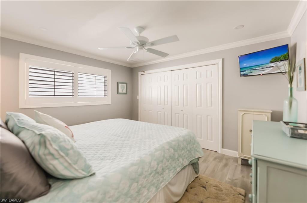Bedroom featuring ornamental molding, light wood finished floors, a closet, and a ceiling fan