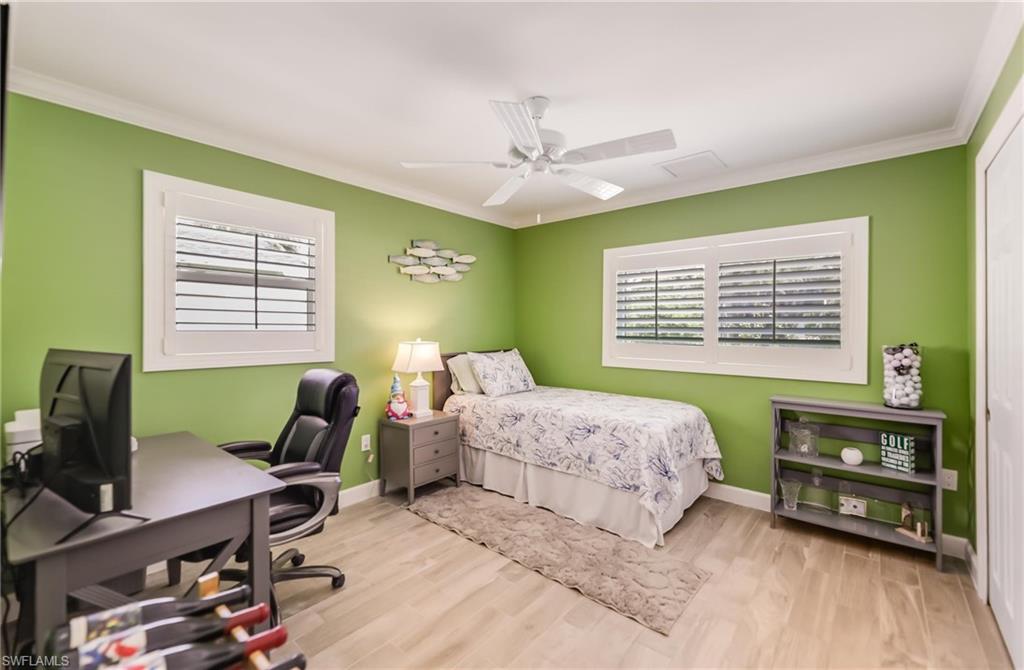 Bedroom with multiple windows, a desk, crown molding, wood finished floors, and ceiling fan