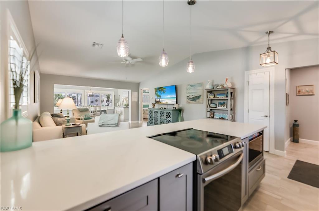 Kitchen with appliances with stainless steel finishes, gray cabinetry, a ceiling fan, lofted ceiling, and open floor plan