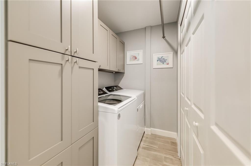 Washroom featuring cabinet space, washing machine and clothes dryer, and light wood-style flooring