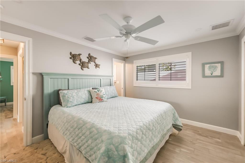 Bedroom with ornamental molding, ceiling fan, and light wood-style flooring