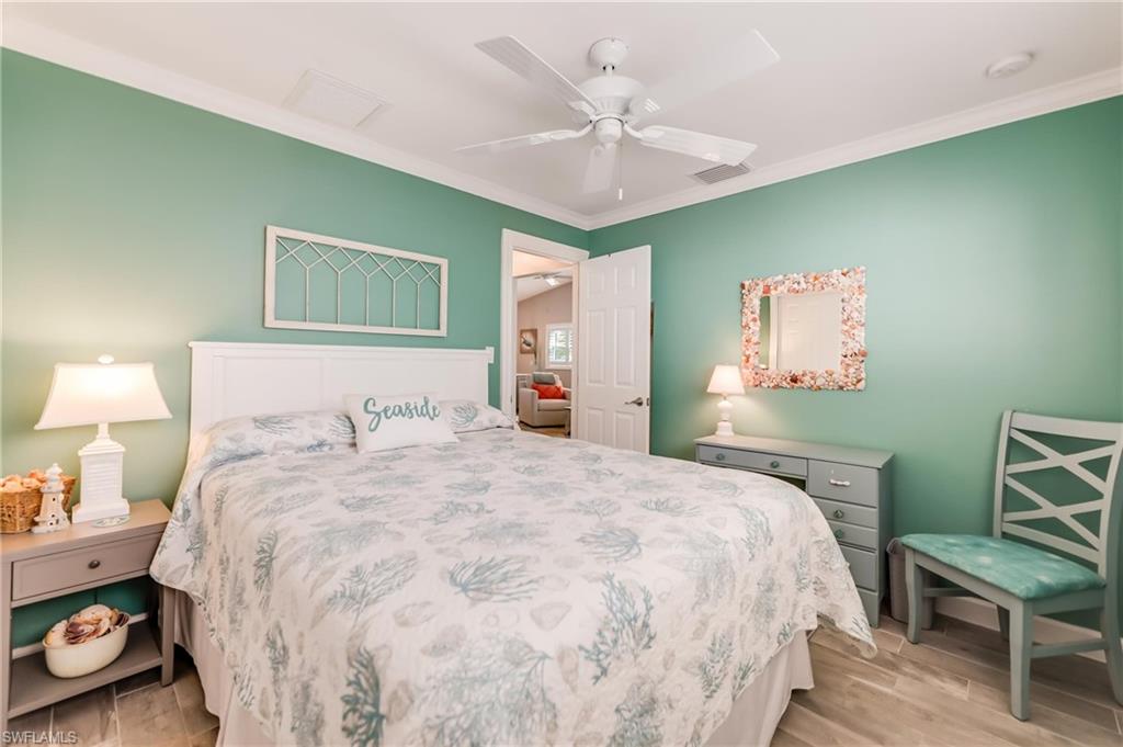Bedroom featuring light wood finished floors, ornamental molding, and ceiling fan