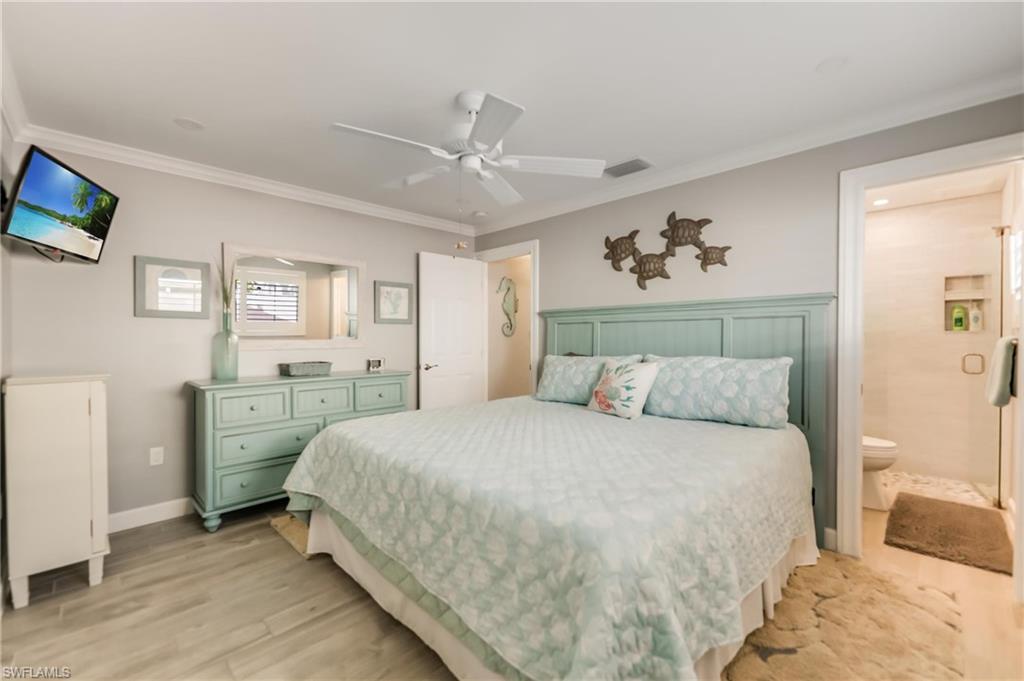 Bedroom featuring light wood-style floors, ornamental molding, ensuite bathroom, and ceiling fan