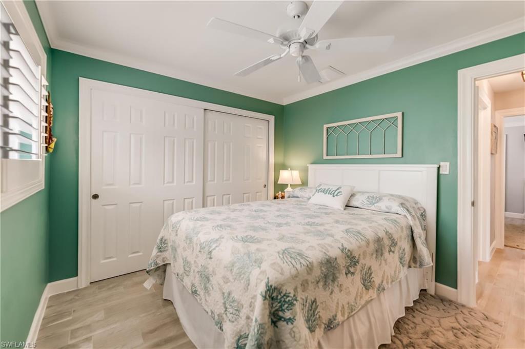 Bedroom featuring light wood-style flooring, a closet, ornamental molding, and a ceiling fan