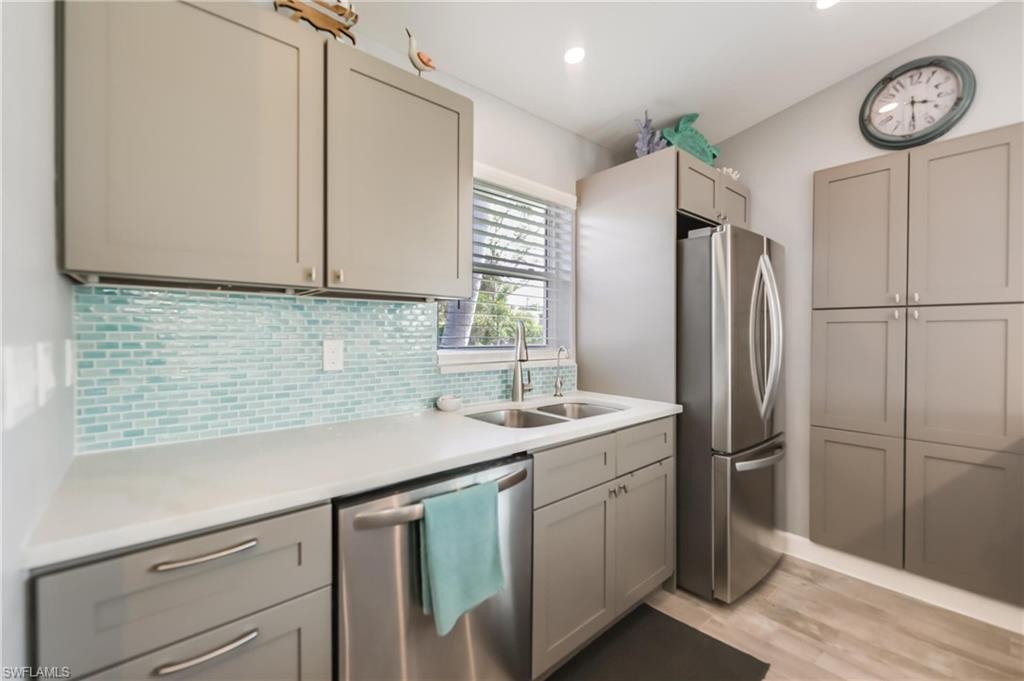 Kitchen with appliances with stainless steel finishes, light countertops, light wood finished floors, tasteful backsplash, and gray cabinets