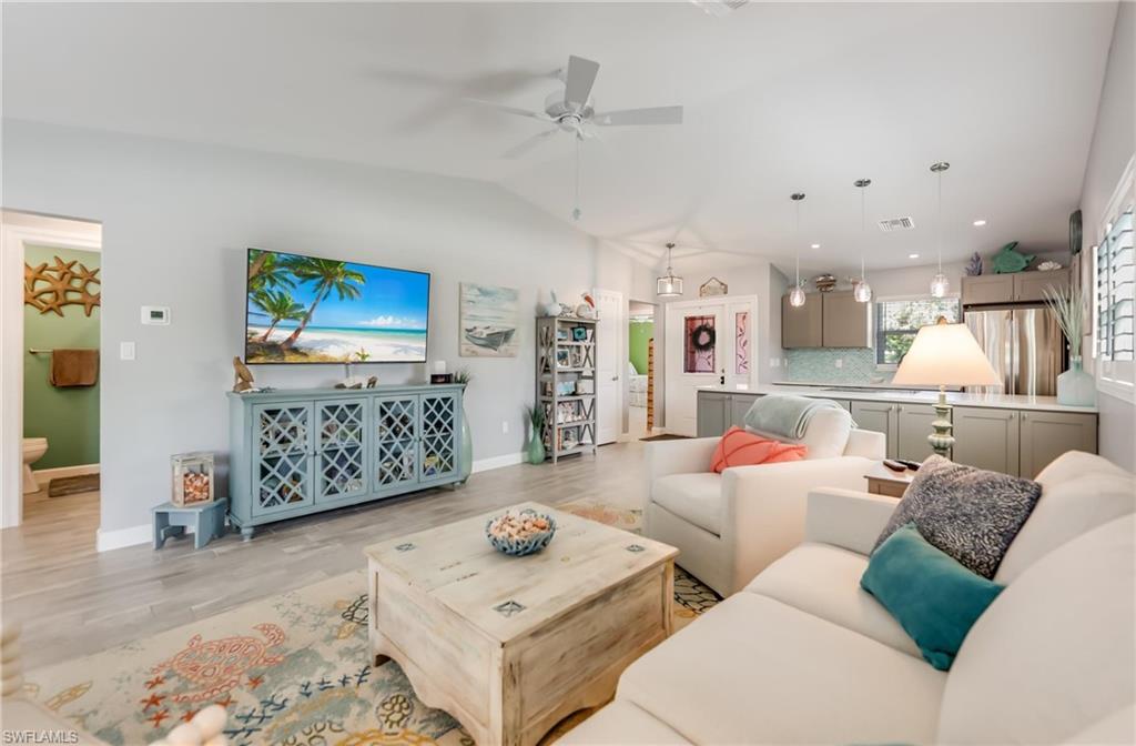 Living area with light wood-type flooring, lofted ceiling, and a ceiling fan