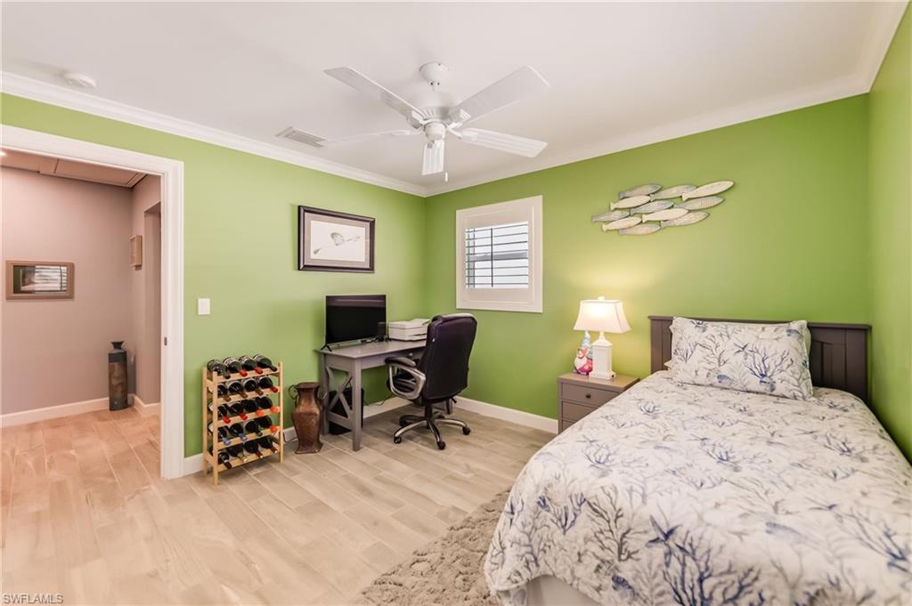 Bedroom with ornamental molding, wood finished floors, and ceiling fan