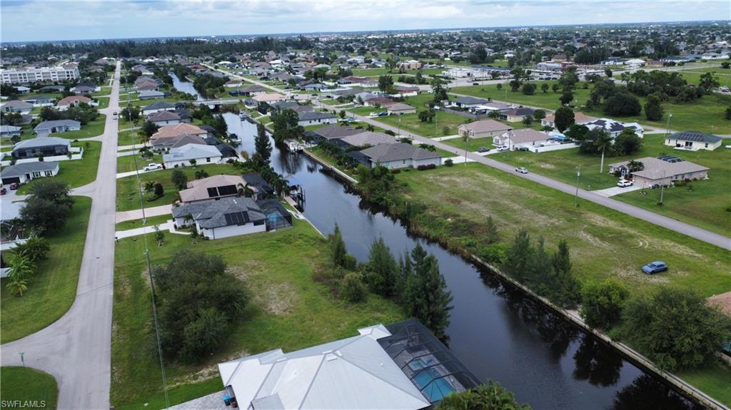 Aerial view of property and surrounding area featuring a nearby body of water and nearby suburban area