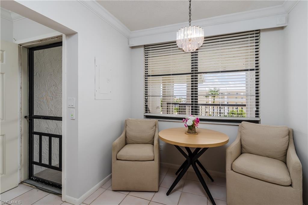 Sitting room with ornamental molding, a chandelier, light tile patterned floors, and electric panel
