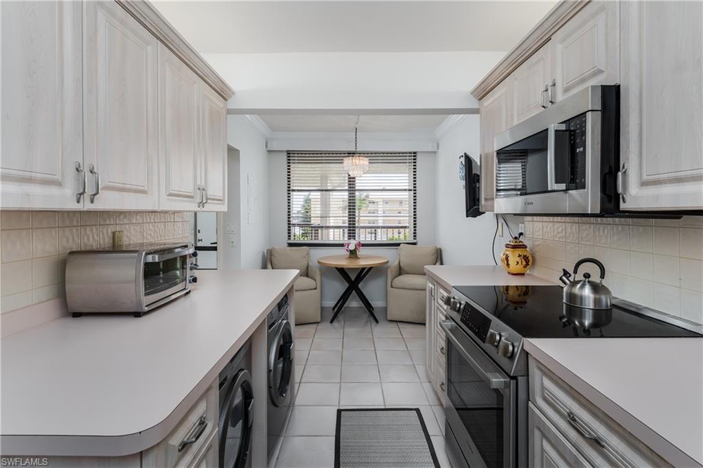 Kitchen featuring  tile backsplash, stainless steel appliances, washing machine and dryer,