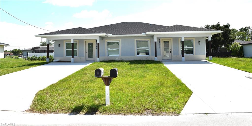 View of front of home with driveway, a front yard, and stucco siding