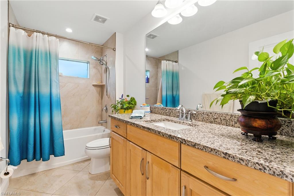 Full bathroom with shower / bath combo with shower curtain, vanity, and light tile patterned flooring