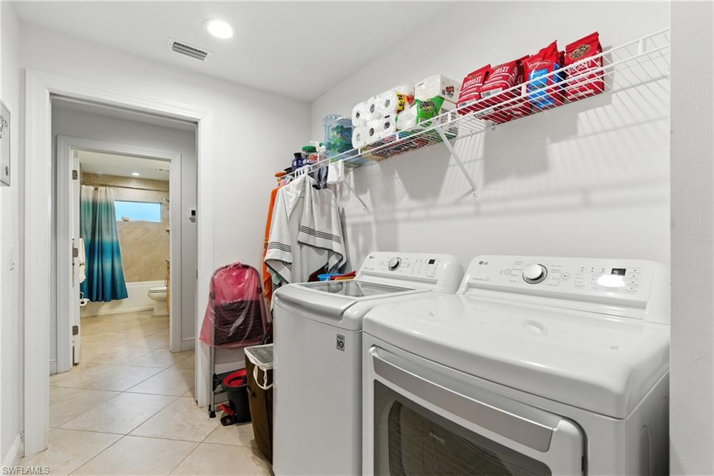 Washroom featuring light tile patterned floors, washing machine and dryer, and recessed lighting