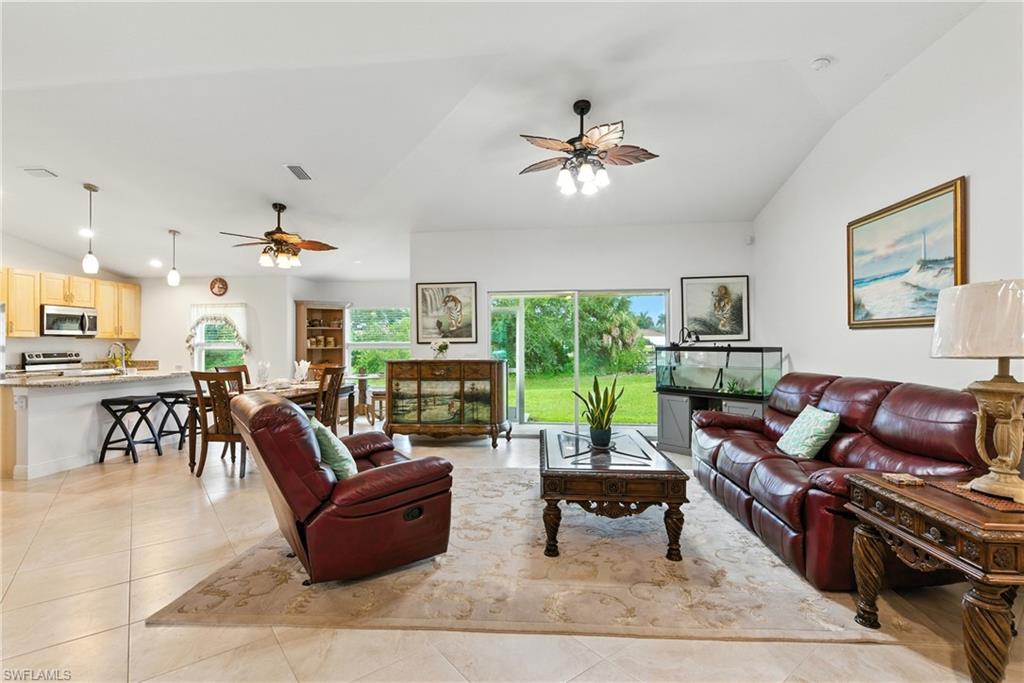 Living area featuring lofted ceiling, light tile patterned flooring, and ceiling fan