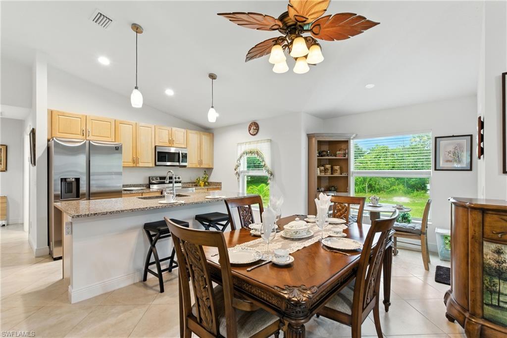 Dining space featuring lofted ceiling, recessed lighting, light tile patterned flooring, and ceiling fan