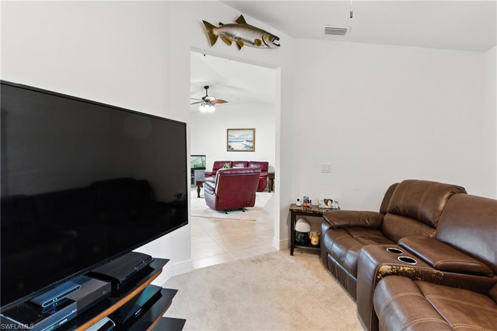 Living room with light colored carpet, light tile patterned flooring, and ceiling fan