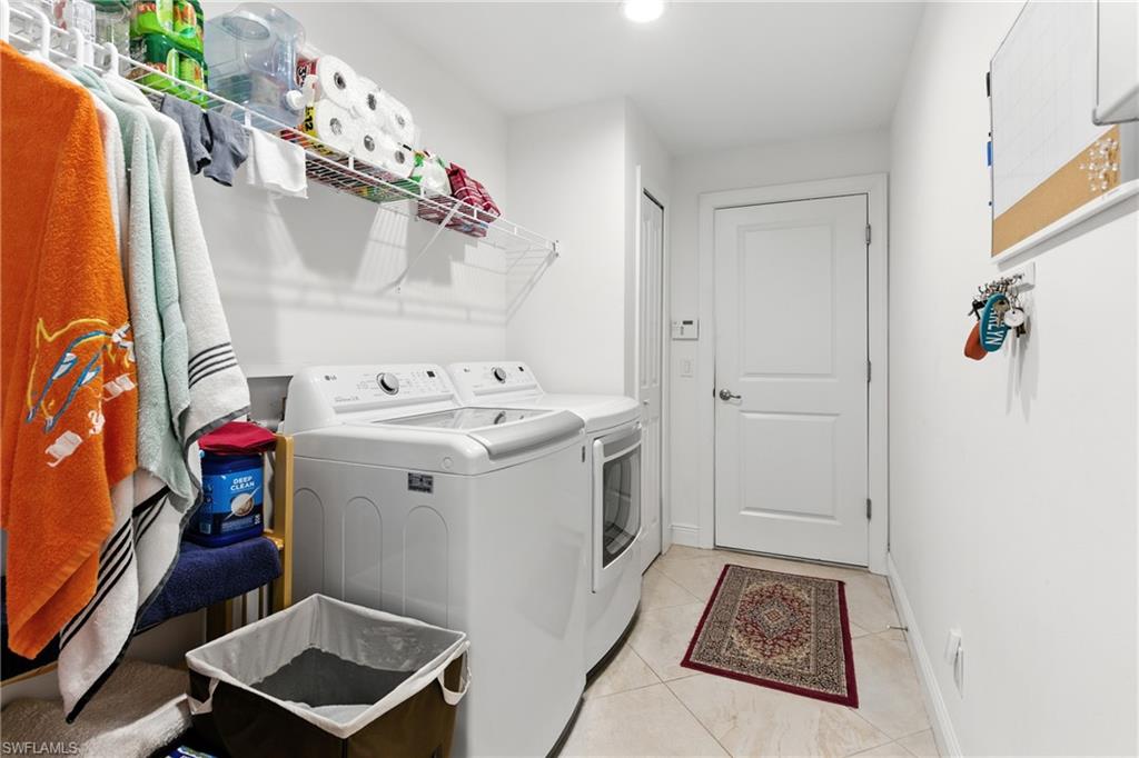 Washroom featuring light tile patterned flooring, washing machine and clothes dryer, and recessed lighting