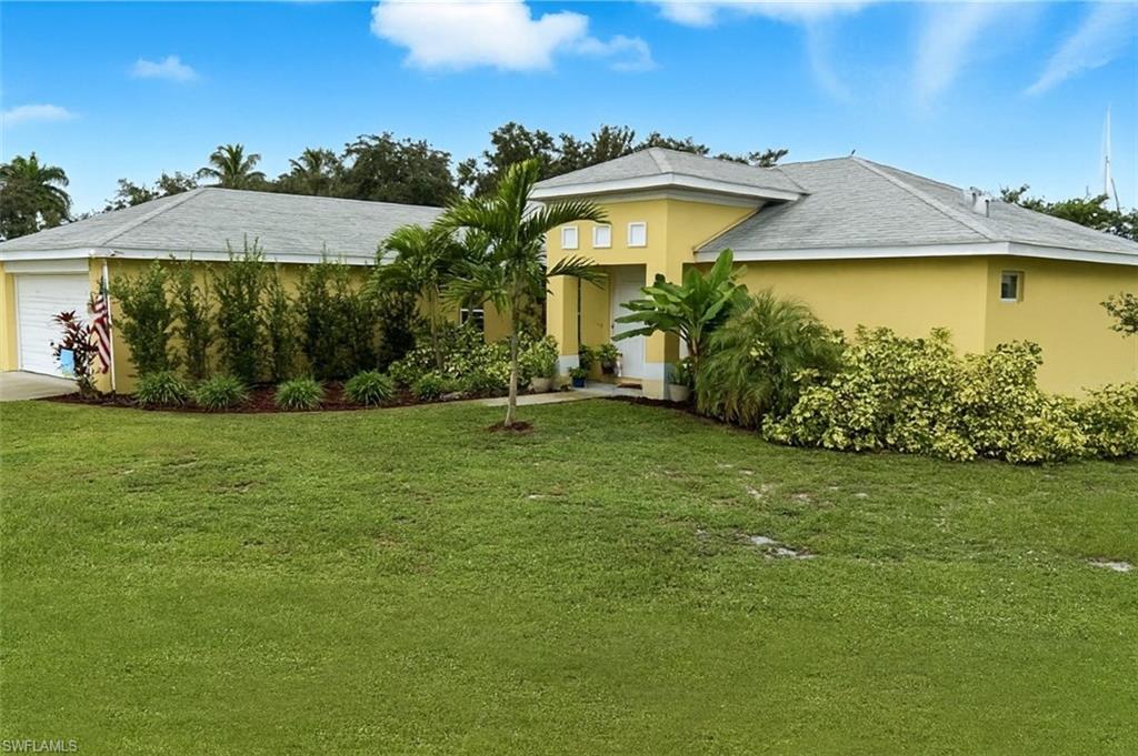Single story home with a front lawn, stucco siding, and a garage