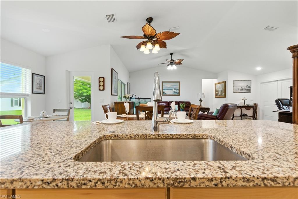 Kitchen with open floor plan, light stone counters, and vaulted ceiling