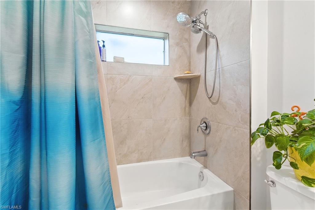 Bathroom featuring shower / bathtub combination with curtain and toilet