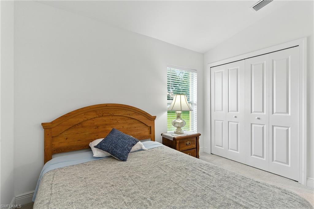 Bedroom featuring light carpet, a closet, and vaulted ceiling