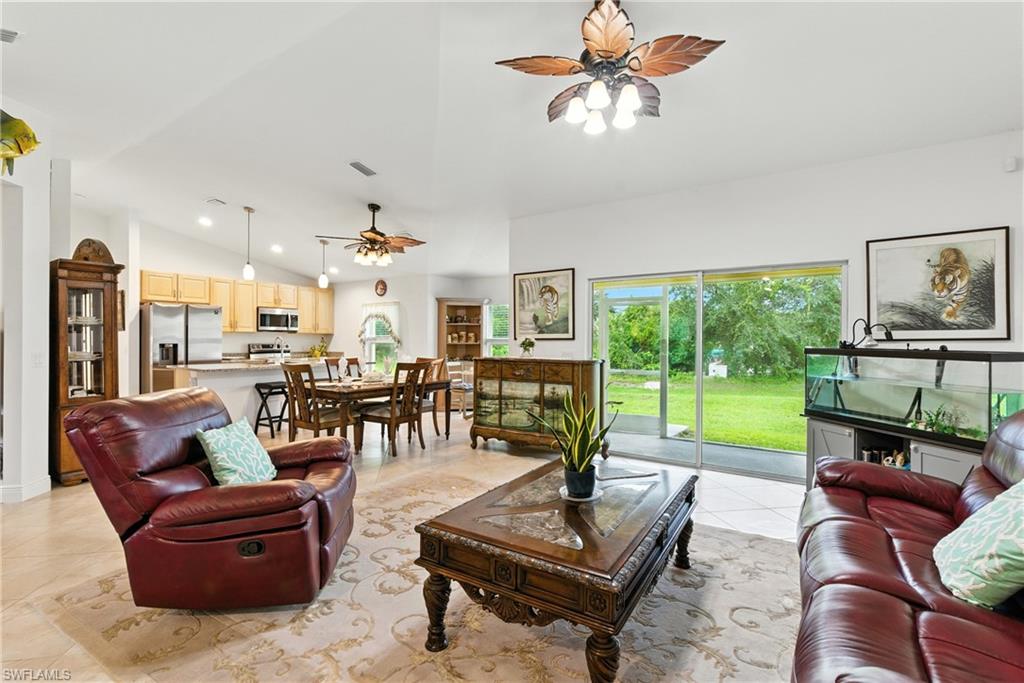 Living room featuring a ceiling fan, high vaulted ceiling, and light tile patterned floors