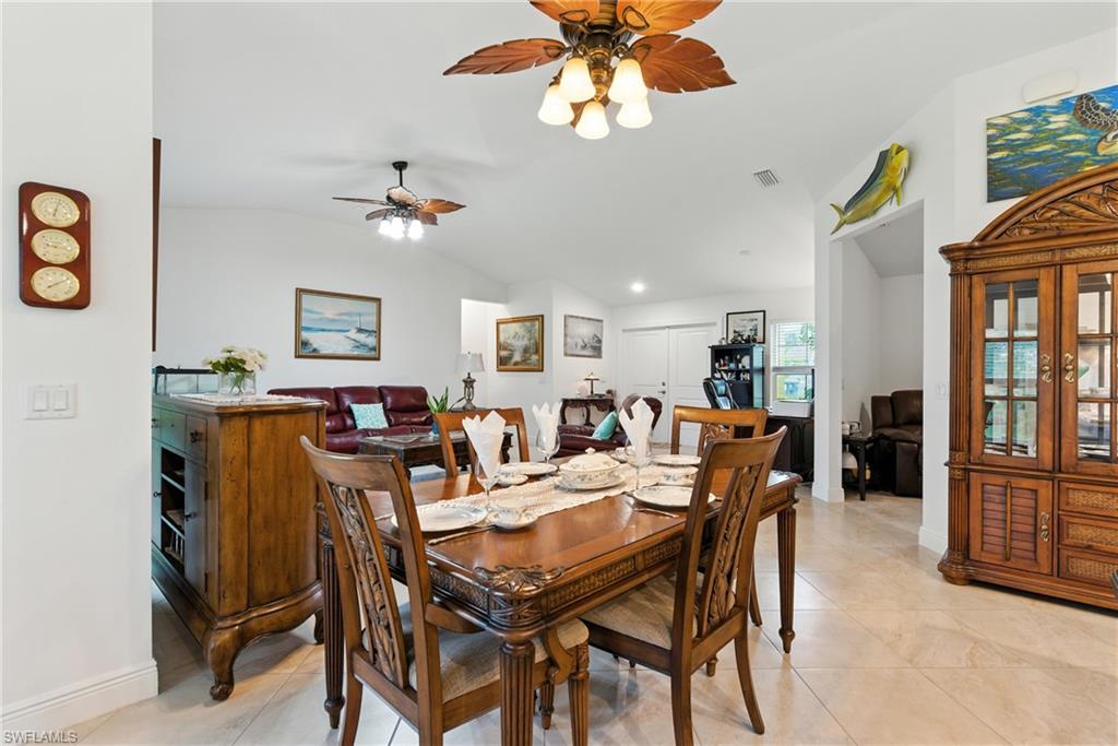Dining area with lofted ceiling, light tile patterned floors, and ceiling fan