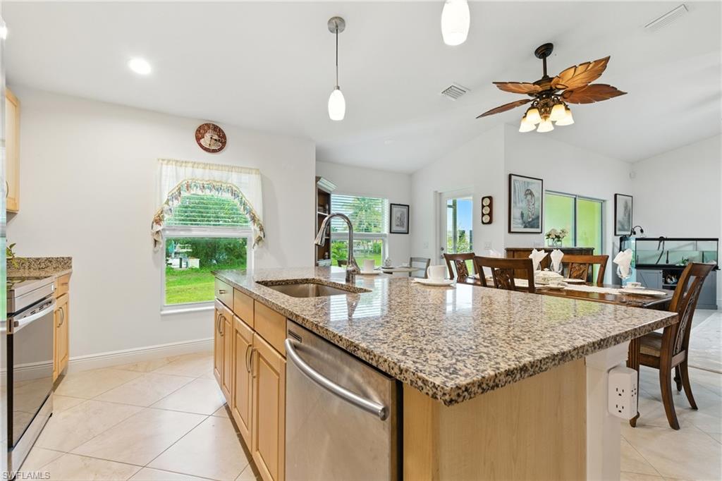 Kitchen featuring light stone countertops, appliances with stainless steel finishes, light brown cabinets, hanging light fixtures, and recessed lighting