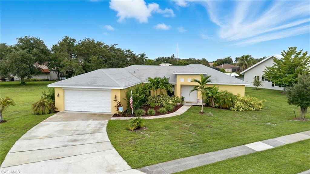 Ranch-style house with a front yard, stucco siding, and driveway