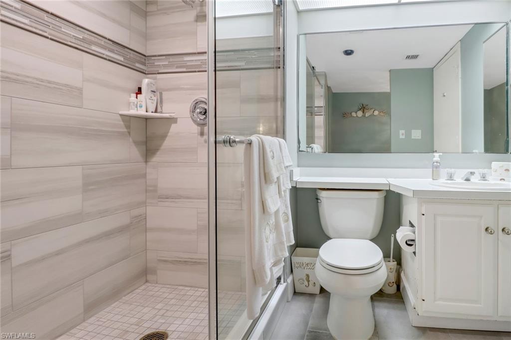Bathroom featuring vanity, an enclosed shower, tile patterned flooring, and toilet