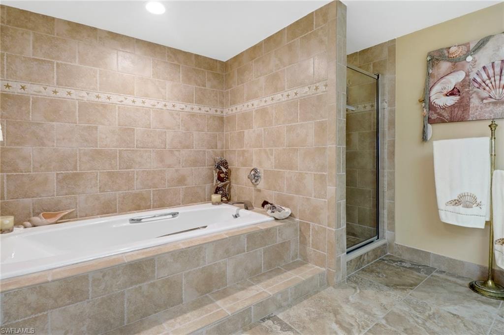Bathroom with tile walls, tile patterned floors, and separate shower and tub